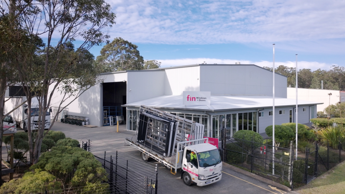 A picture of fin windows factory with a truck taking windows to a client