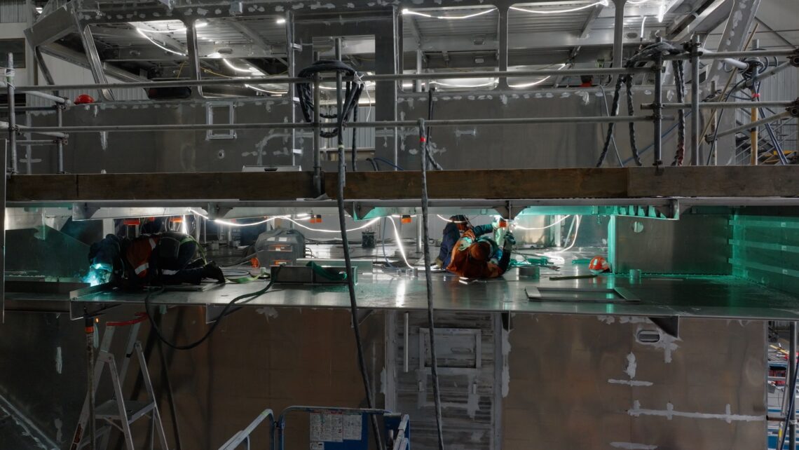 A photo of one of Austal's employees building a large ship with aluminium